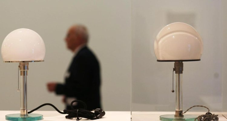FW062A Bonn, Germany. 31st Mar, 2016. A man walks past an original desk lamp by Wilhelm Wagenfeld (R) and a replica (L) in Bonn, Germany, 31 March 2016. The exhibition 'Das Bauhaus - Alles ist Design' (lit. The Bauhaus - everything is design) will run at the Bundeskunsthalle (German Federal Art and Exhibition Hall) from 01 April to 14 August 2016. Photo: OLIVER BERG/dpa/Alamy Live News