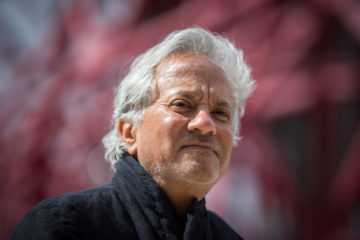 LONDON, ENGLAND - APRIL 26:   Anish Kapoor poses for photographers in front of the ArcelorMittal Orbit tower at the Queen Elizabeth Olympic Park on April 26, 2016 in London, England.  Tickets for The Slide, the world's tallest and longest tunnel slide, created by artists Anish Kapoor and Carsten Holler went on sale today.  The 178 metre slide from the top of the ArcelorMittal Orbit, which will open on June 24, takes 12 turns with riders expected to reach 15 miles per hour before reaching the ground.    (Photo by Rob Stothard/Getty Images)
