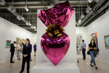 Visitors stand next to an artwork by Jeff Koons entitled "Sacred Heart (Magenta/Gold)" at the Gagosian gallery exhibition space during a preview day of Art Basel, the world's premier modern and contemporary art fair, on June 12, 2019 in Basel. - Thousand of art collectors, art dealers, artists, curators and art lovers are expected to attend the annual meeting place of the art community with 290 of the world's leading galleries showing the works of over 4,000 artists. (Photo by FABRICE COFFRINI / AFP)        (Photo credit should read FABRICE COFFRINI/AFP/Getty Images)